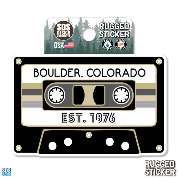 Rugged sticker shaped like a cassette tape with the text “Boulder, Colorado” and “Est. 1876” in black and gold.